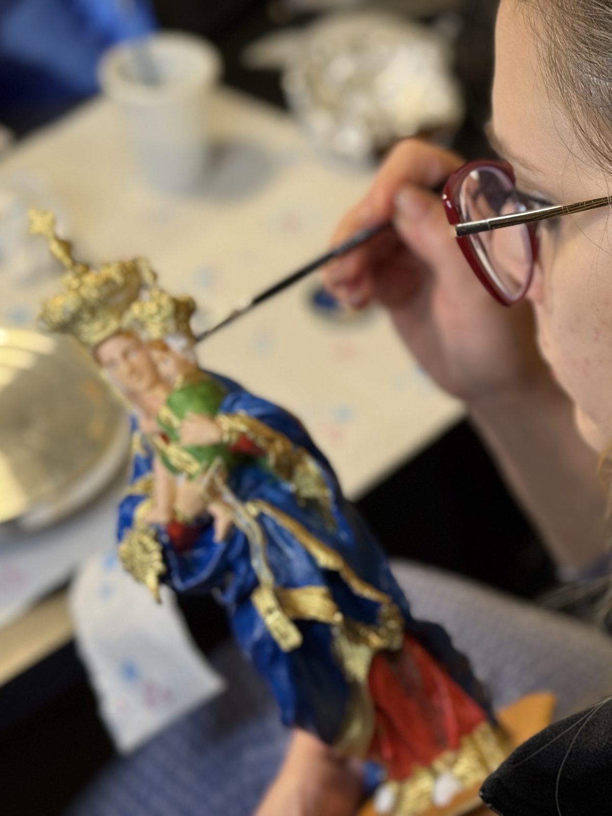 Mariassunta Telesca mentre dipinge e dora a mano una statua della Madonna
